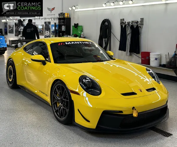 A side profile of the yellow car highlighting mirror-like reflections on the clean door panels and fenders under professional studio lighting.