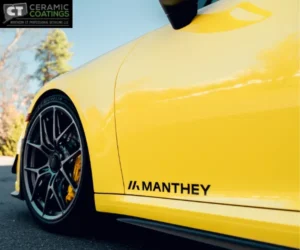 A side profile of the yellow car highlighting mirror-like reflections on the clean door panels and fenders under professional studio lighting.