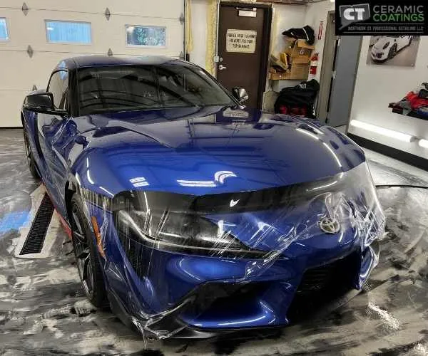 showing clear paint protection film being meticulously applied over the front bumper and emblem, as seen in paint protection film