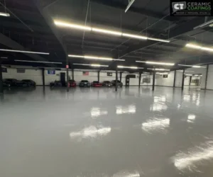 Wide interior shot of a spacious climate-controlled storage facility with polished grey floors housing multiple luxury and sports cars